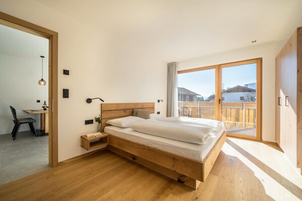 A modern bedroom with a wooden bed, a desk, and a chair.