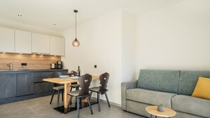 A modern kitchen with a dining area, a grey sofa, and a small round table with a plant. - Apartment "Sunnig - Sonennschein" with Mountain View, Balcony & Wi-Fi (Völlan)
