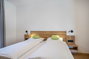 A double bed with a wooden headboard, two bedside tables with lamps, and a window with curtains.