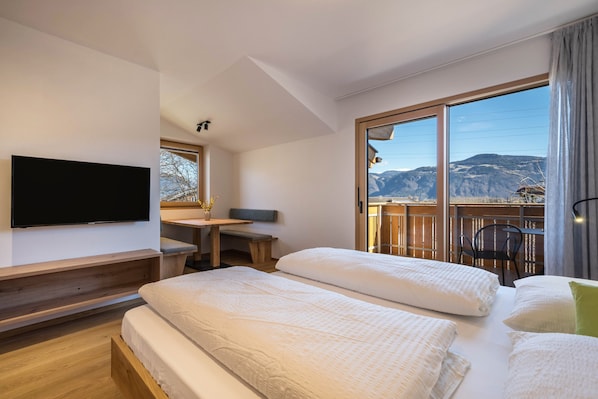 Habitación de hotel con dos camas, televisor, escritorio y vistas a las montañas.