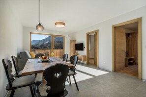 Un comedor moderno con una mesa de madera, sillas y vistas a montañas a través de amplios ventanales.