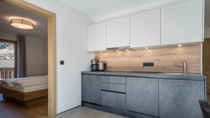 Een moderne keuken met grijze kastjes, een houten aanrecht en een ingebouwde kookplaat.