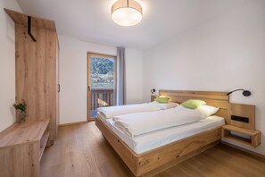 Un dormitorio con cama de madera, mesita de noche, lámpara colgante y ventana con vista a la montaña.