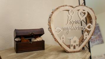 A wooden heart-shaped sign with the words 'Love Home' and small house cutouts, placed on a table next to a dark wooden chest with decorative items.