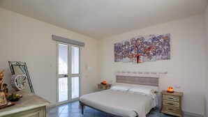 Une chambre à coucher comprenant un lit, des tables de chevet, une commode et un grand tableau abstrait accroché au mur.