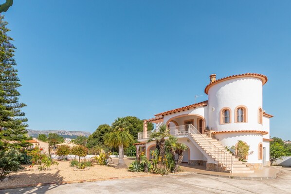A white building with a round tower, a balcony, and a staircase leading to the entrance. - Villa 'Merced Planta Baja' with Mountain View, Private Pool and Wi-Fi (Calpe)