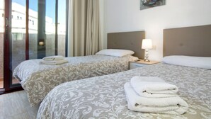 Habitació d'hotel amb dos llits, una finestra amb cortines, una làmpada i un quadre a la paret.