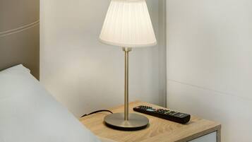 A bedside table with a lamp, a remote control, and a drawer.