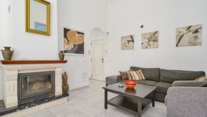 Una sala de estar con chimenea, un sofá, una mesa de centro y cuadros en la pared.
