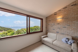 A room with a large window, a brick wall, and a beige sofa.