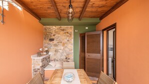 Un espace repas avec un mur en pierre, un plafond en bois et une table entourée de chaises.