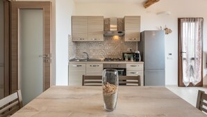 Une cuisine moderne avec des meubles en bois, un réfrigérateur en acier inoxydable et une table à manger agrémentée d’un vase en verre.