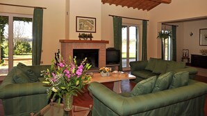 A living room with green sofas, a fireplace, and a television. - Villa in Lazio with Pool and Vineyards (Magliano Sabina)