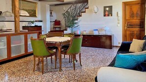 A dining area with a wooden table and chairs, a kitchen in the background, and a staircase leading to another level. - Ca' Nadia Apartment  (Venice)