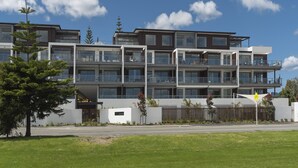 Un immeuble résidentiel à plusieurs étages, doté de balcons, de grandes fenêtres et d’une pelouse bien entretenue.