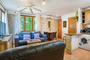 Un espace de vie compact comprenant un canapé, une table à manger, un lave-linge et un ventilateur de plafond.