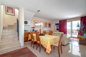 A dining area with a table set for six, a sofa, and a staircase.