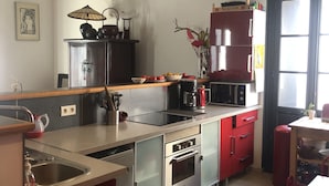 A modern kitchen with stainless steel appliances, wooden beams, and a red cabinet.