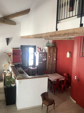 A kitchen with a wooden island, a dining area with red chairs, and a red wall.
