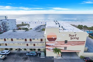 A hotel with a beach view, a parking lot, and a building with a 'Surf Song' mural.