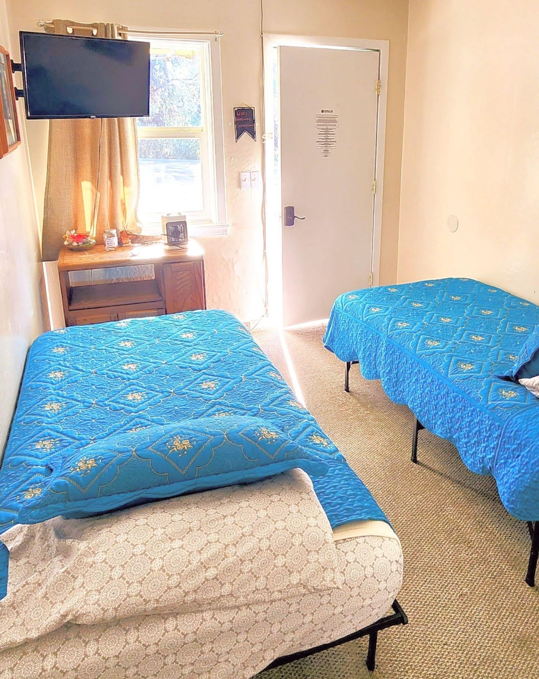 Una habitación con dos camas, televisión, escritorio y puerta.