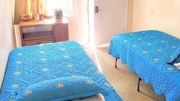 Una habitación con dos camas, televisión, escritorio y puerta.