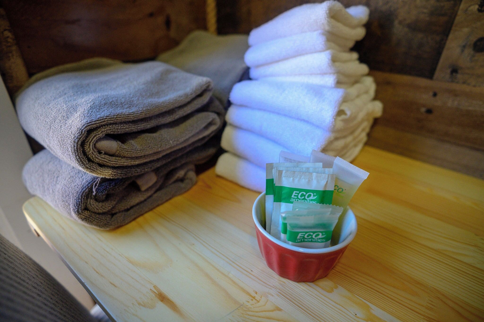 A stack of folded towels and a cup with ECO amenities.