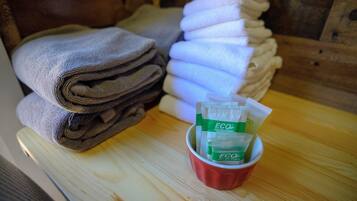 A stack of folded towels and a cup with ECO amenities.