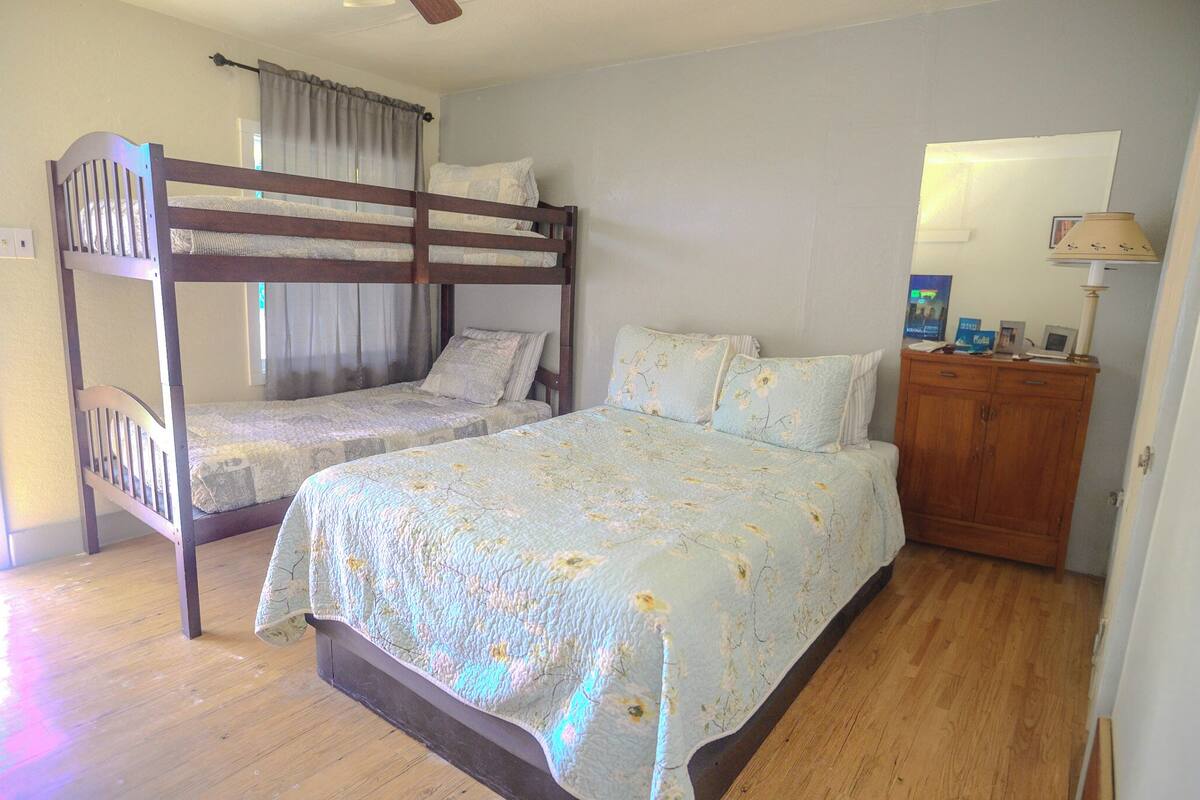 A room with two bunk beds, a wooden dresser, a mirror, and a lamp.