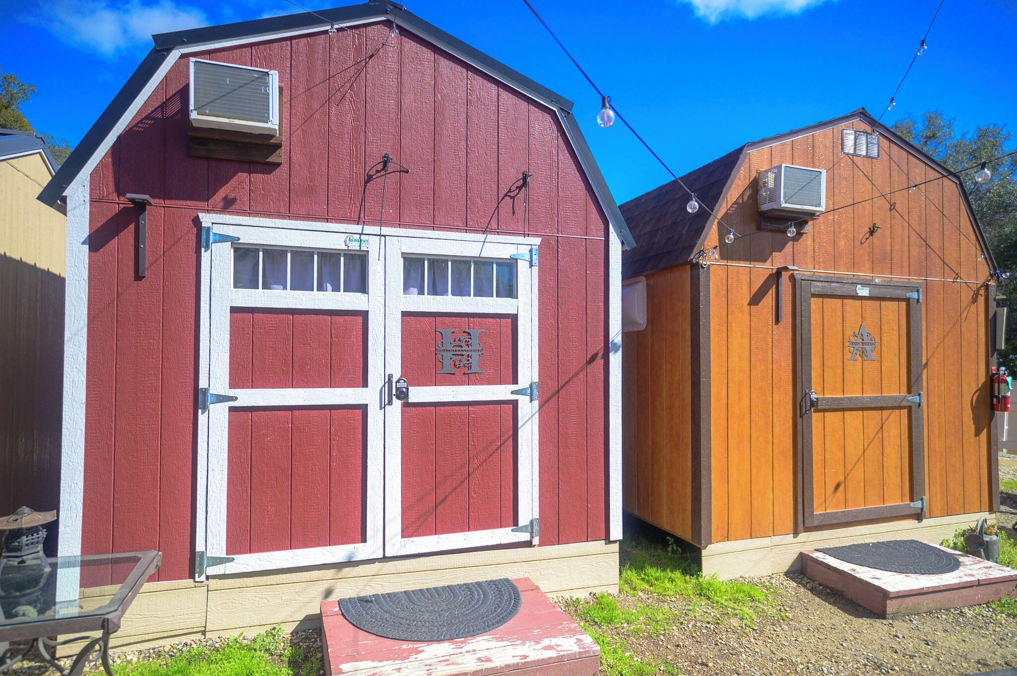 A red barn with a white door and an attached wooden shed with a brown door.