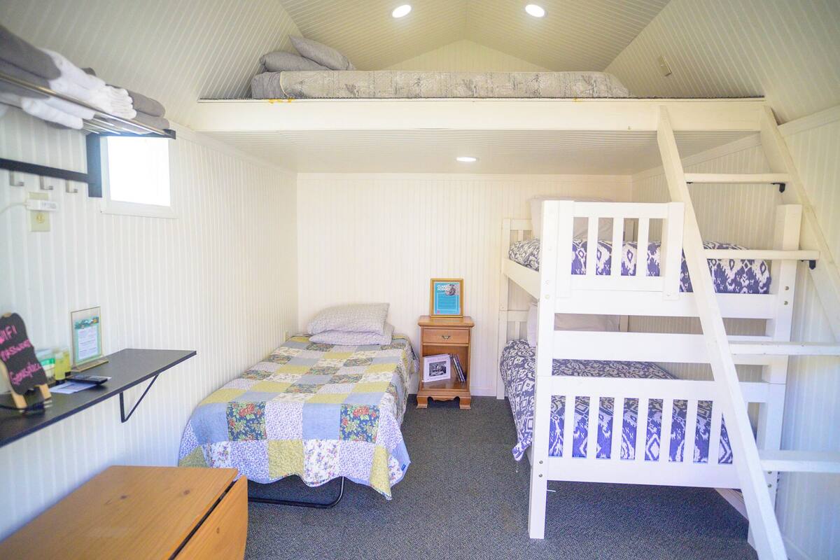 A compact bedroom with bunk beds, a desk, and a small window.
