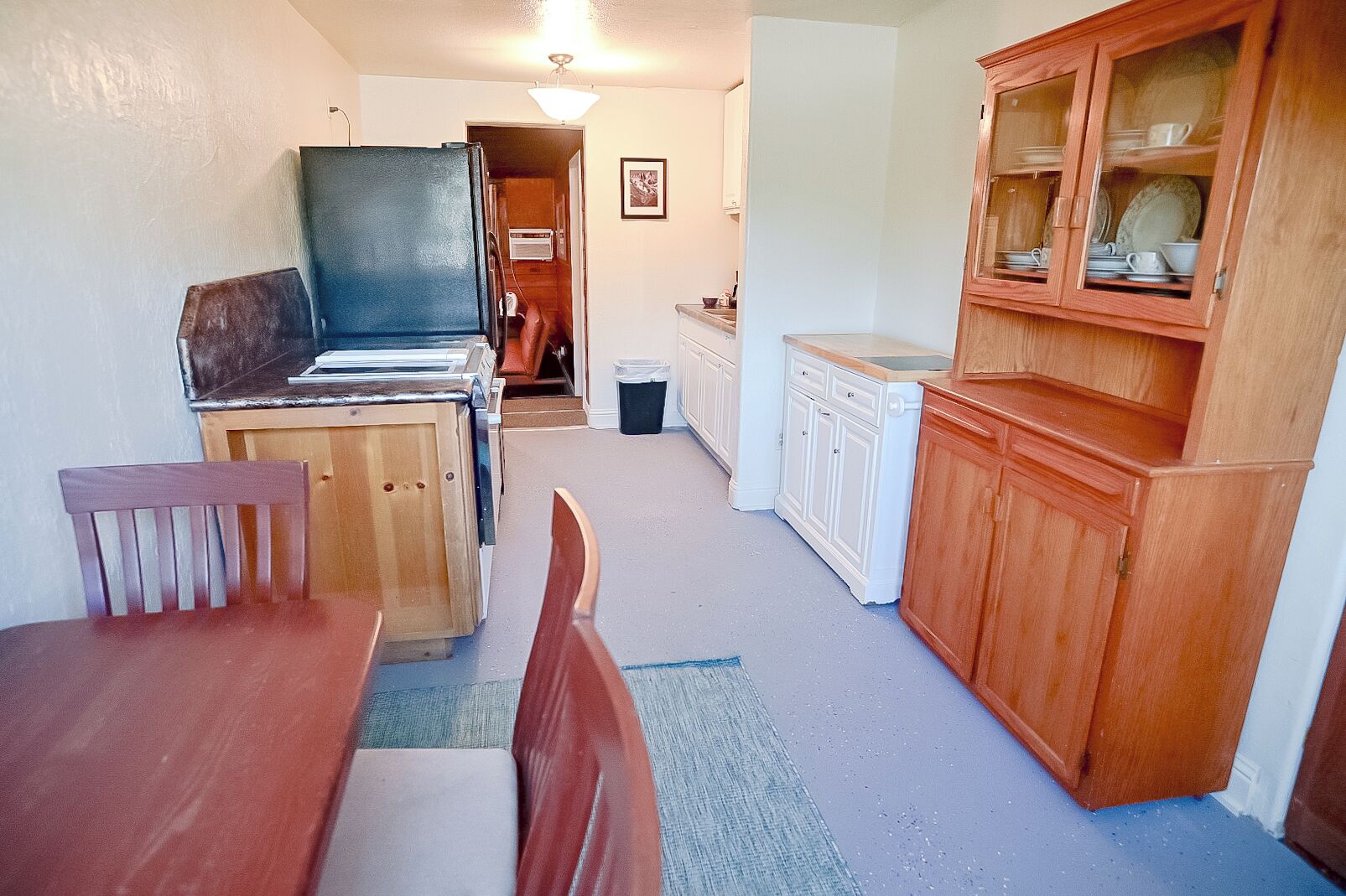 A compact kitchen with wooden cabinets, a dining table, and chairs.