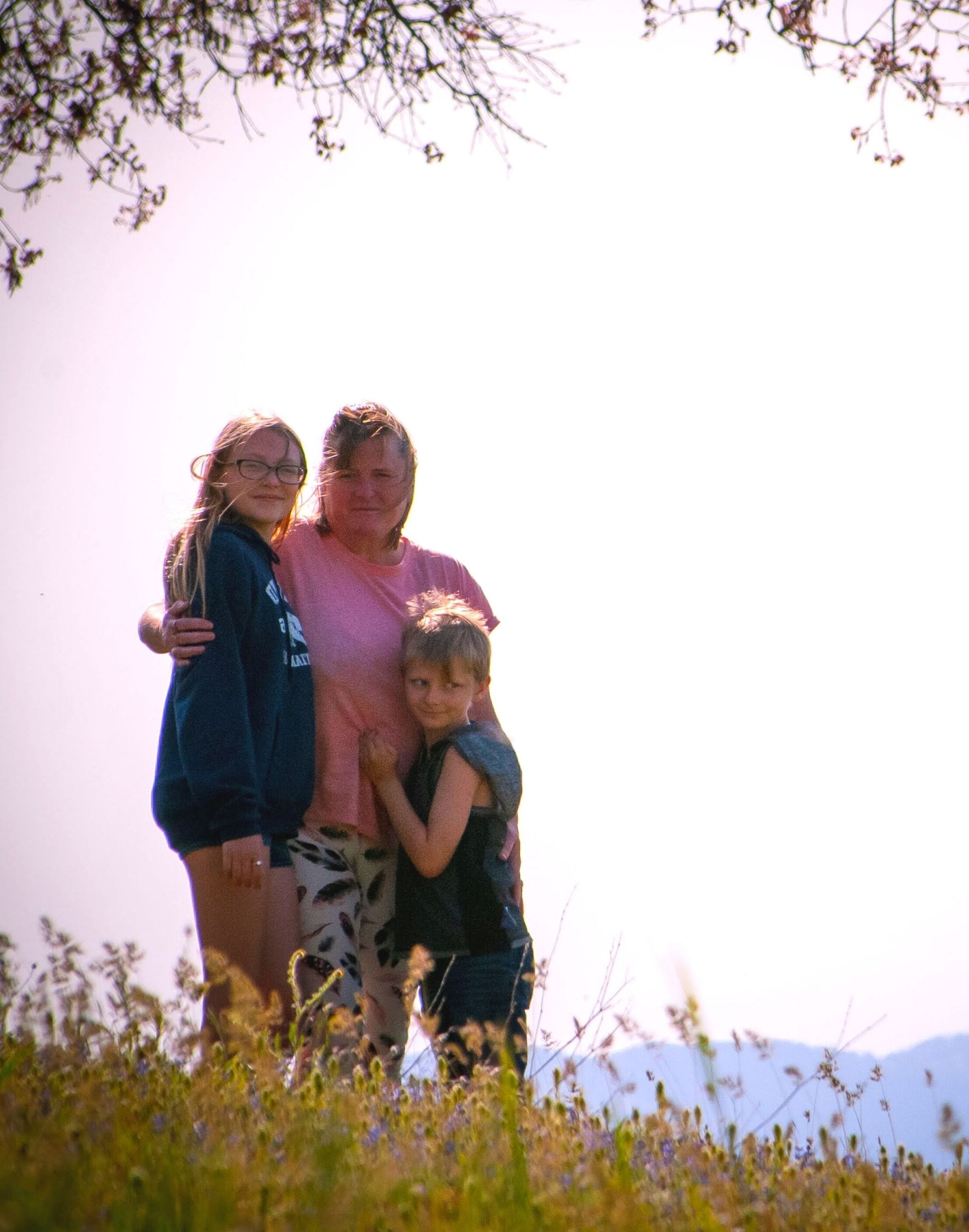 A family of three in a natural outdoor setting with a clear sky.