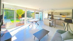 Ein moderner, offener Wohnbereich mit Küche, großen Schiebeglasüren zum Garten und einem Esstisch.