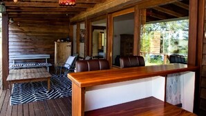 Un interior de madera con un banco largo, una mesa y vistas al exterior.