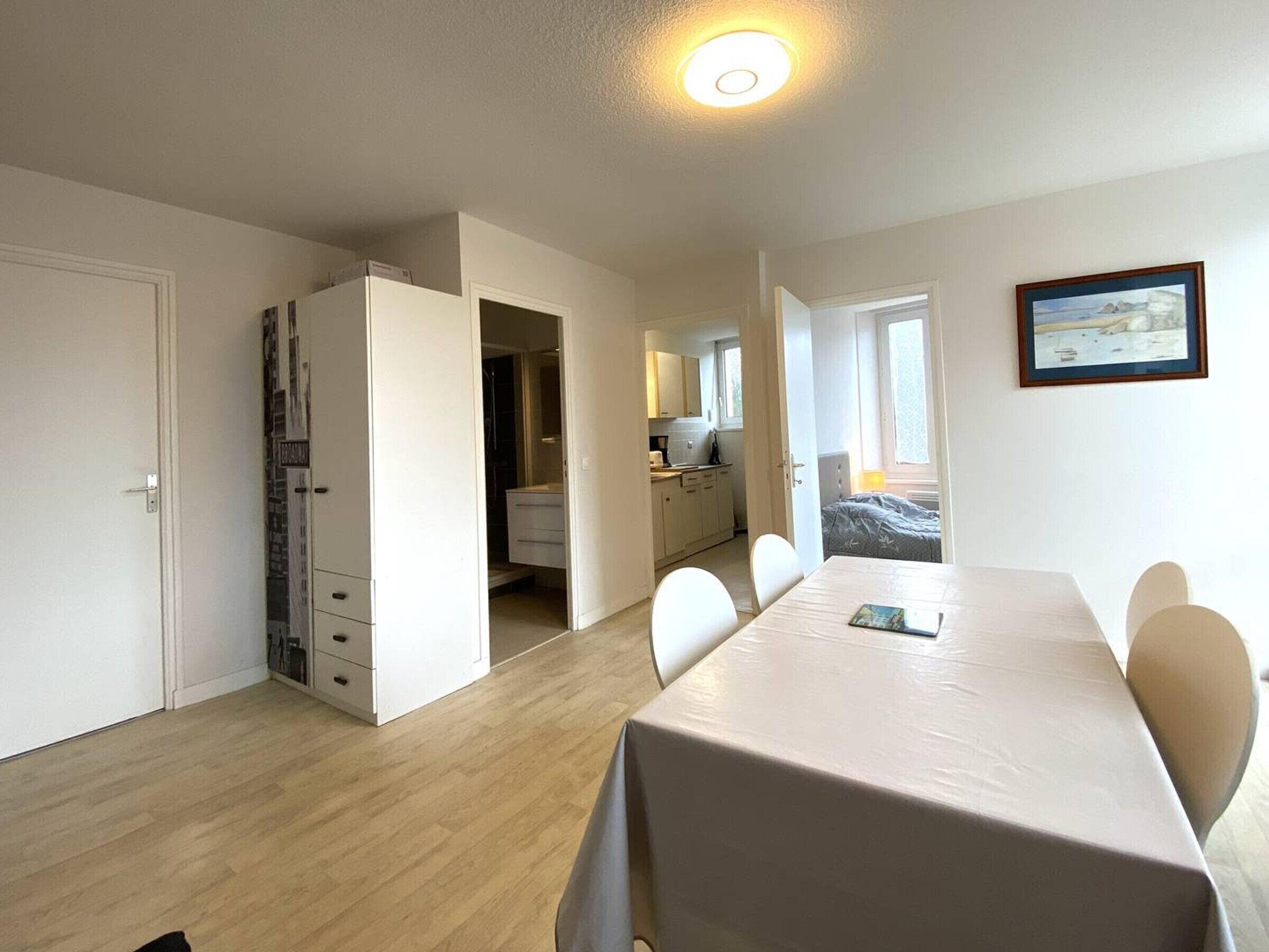 Habitación compacta con una mesa de comedor, sillas, armario y una pequeña kitchenette.
