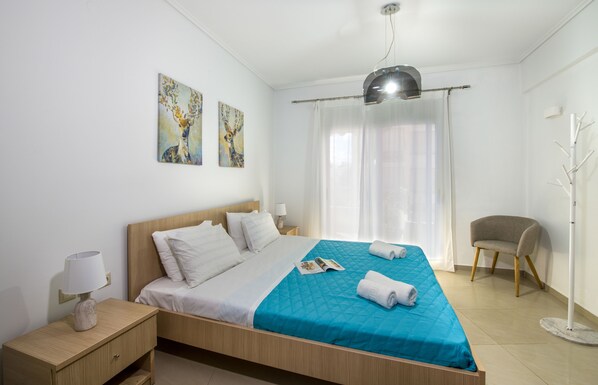 A neatly arranged hotel room with a bed, a chair, a lamp, and artwork on the wall.