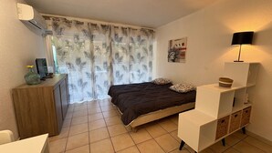 Quarto com cama, escrivaninha, luminária e ar-condicionado fixado na parede.
