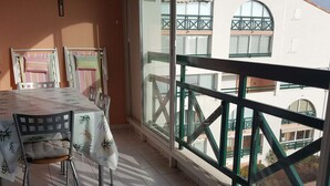 A balcony with a table and chairs, a railing, and a view of buildings. - Duplex 3-room apartment with pool, air conditioning and garage in Port Camargue (Port Camargue)