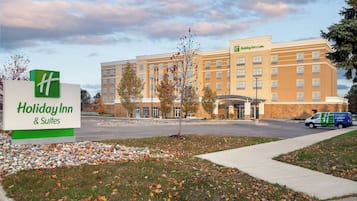A Holiday Inn & Suites building with a large sign, a parking lot, and a delivery van.