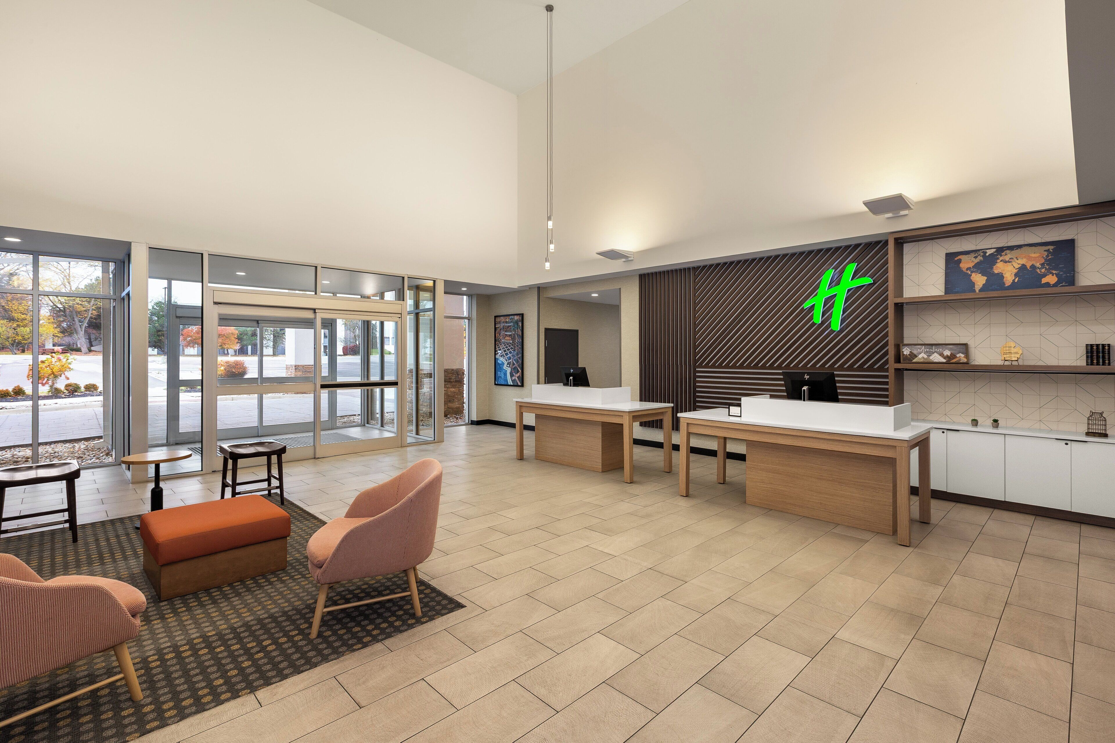 A spacious lobby with a reception desk, seating area, and large windows offering a view of the outdoors.