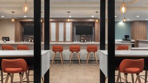 A modern kitchen with a central island, bar stools, pendant lighting, and a flat-screen TV. - Holiday Inn & Suites Detroit - Troy by IHG (Troy)
