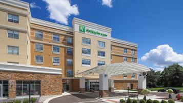 Edificio de Holiday Inn & Suites con entrada cubierta, varias ventanas y un estacionamiento.