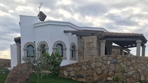 A modern house with a stone facade, arched windows, and a covered porch. - 3 Bedroom Villa in Alghero (Alghero)