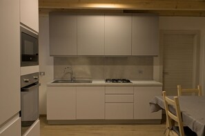 Une cuisine compacte équipée d’un four encastré, d’une cuisinière à gaz et d’un évier.