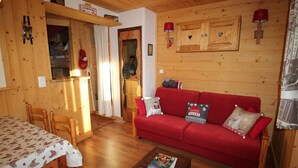 L’intérieur d’un chalet en bois chaleureux, avec un canapé rouge, une table à manger en bois et un coin cuisine.