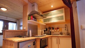 Une cuisine de taille réduite, dotée de meubles en bois, d’un four à micro-ondes, d’une cuisinière et d’un évier.