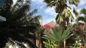 A swimming pool with tiled edges, surrounded by palm trees and flowering plants. - VILLA 4 bedrooms facing the sea swimming pool garden terrace parking comfort for 12 (M'Bour)