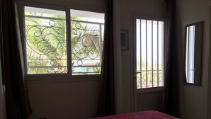 A room with two beds, a window with metal bars, and a door. - VILLA 4 bedrooms facing the sea swimming pool garden terrace parking comfort for 12 (M'Bour)