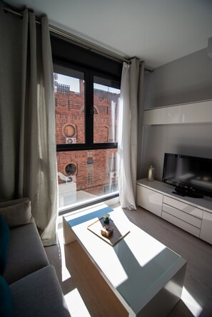 A modern living room with a large window, a flat-screen TV, a sofa, and a coffee table.